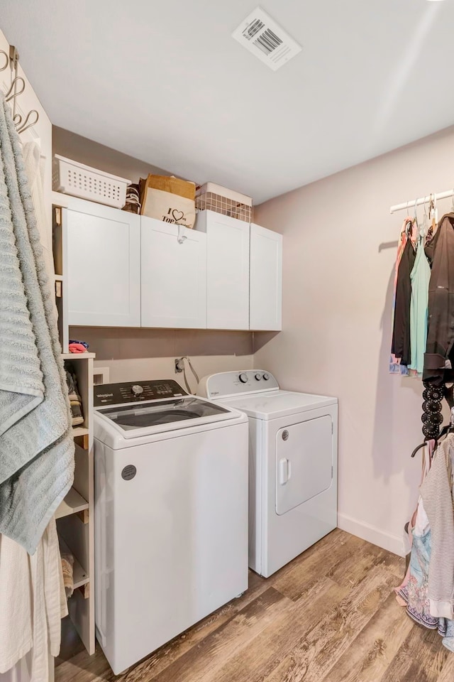 clothes washing area featuring cabinets, separate washer and dryer, and light hardwood / wood-style flooring