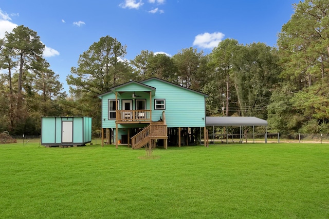 rear view of property with a lawn, ceiling fan, a carport, and a storage shed