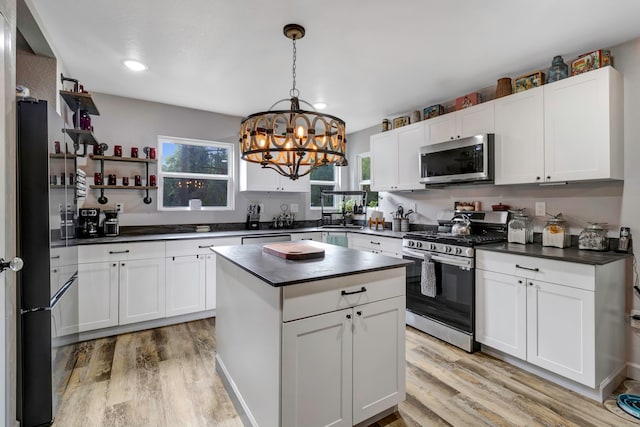 kitchen with white cabinets, stainless steel appliances, a wealth of natural light, and light hardwood / wood-style flooring