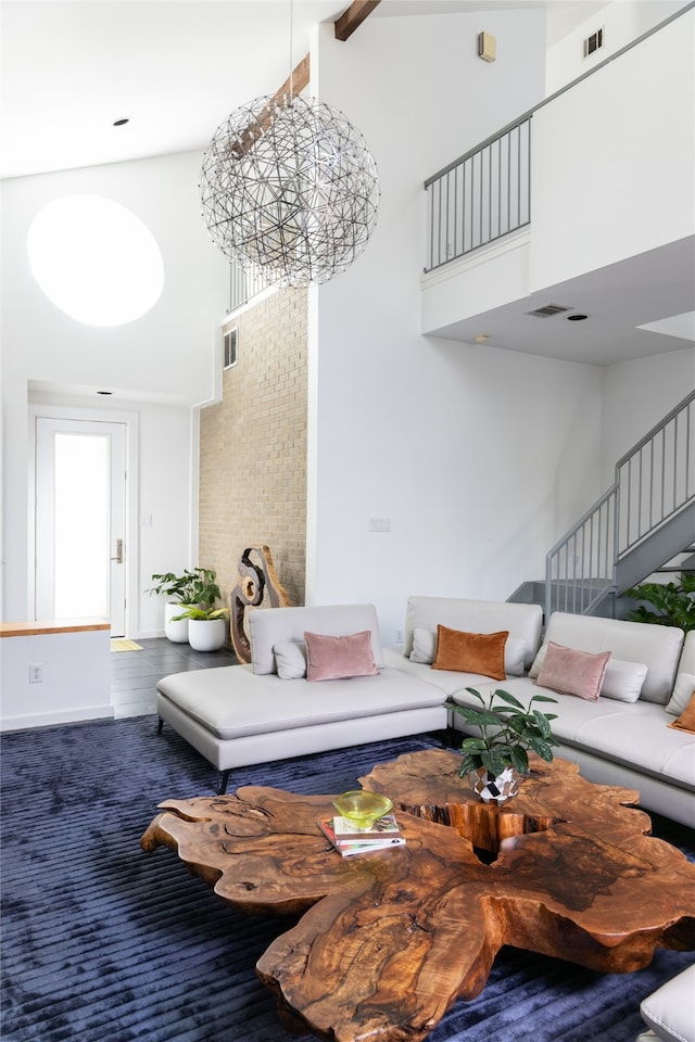 carpeted living room with beam ceiling, a towering ceiling, and an inviting chandelier