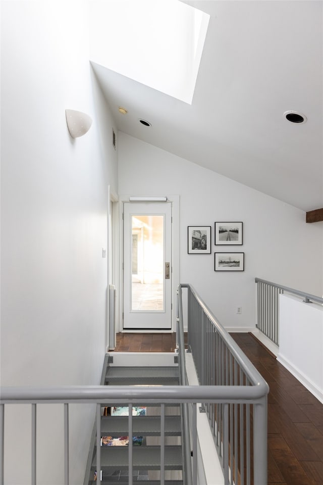 stairway with lofted ceiling with skylight and wood-type flooring