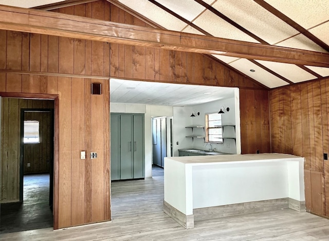 kitchen with wood walls, lofted ceiling with beams, and light hardwood / wood-style floors