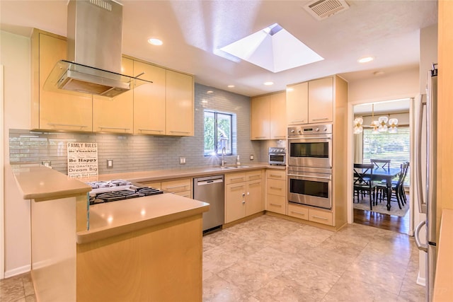 kitchen featuring sink, a skylight, decorative backsplash, island exhaust hood, and stainless steel appliances