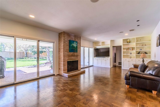 living room featuring built in features, dark parquet floors, and a brick fireplace