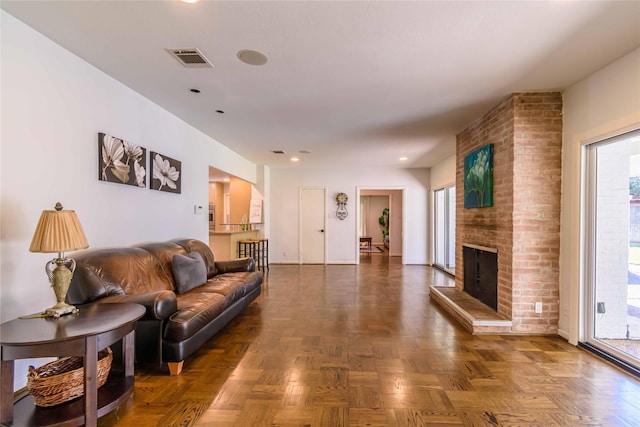 living room featuring dark parquet flooring and a brick fireplace