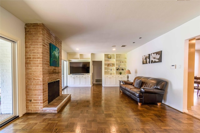 living room featuring built in shelves, dark parquet floors, and a brick fireplace