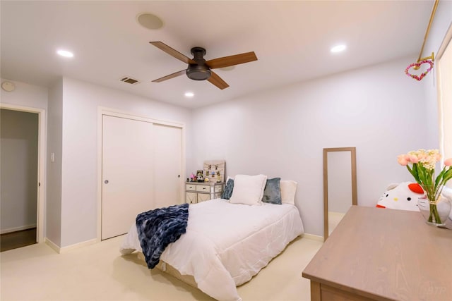 carpeted bedroom with ceiling fan and a closet