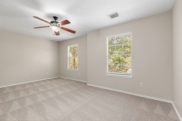 spare room featuring a wealth of natural light, ceiling fan, and light colored carpet