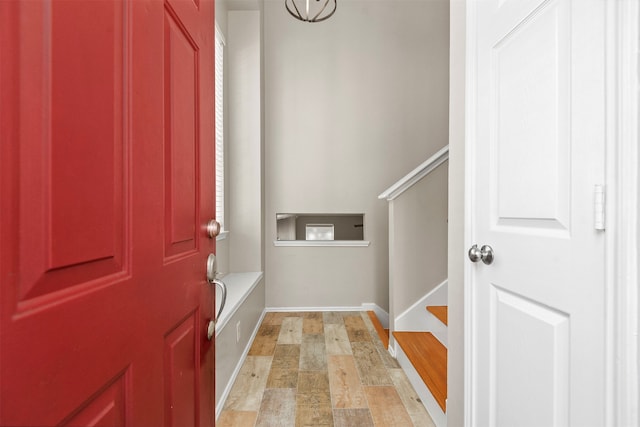 foyer featuring light wood-style flooring, baseboards, and stairs