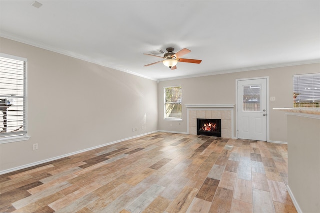 unfurnished living room with ceiling fan, light wood-type flooring, ornamental molding, and a tiled fireplace