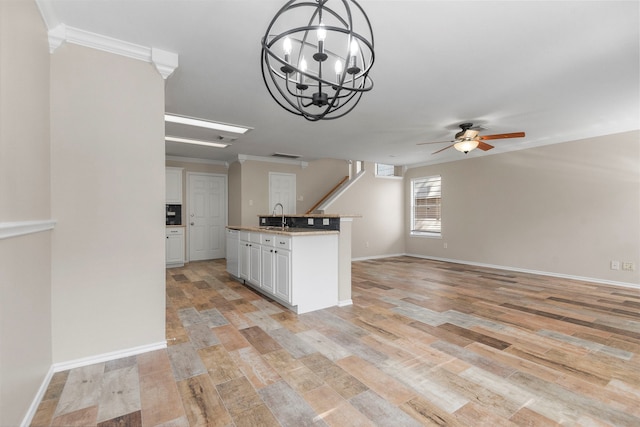 kitchen with ceiling fan with notable chandelier, light wood-type flooring, white cabinetry, and sink