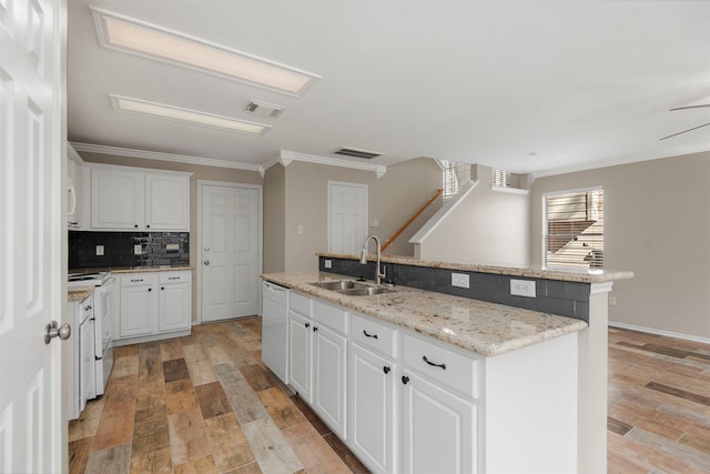 kitchen with white appliances, sink, light hardwood / wood-style floors, and an island with sink