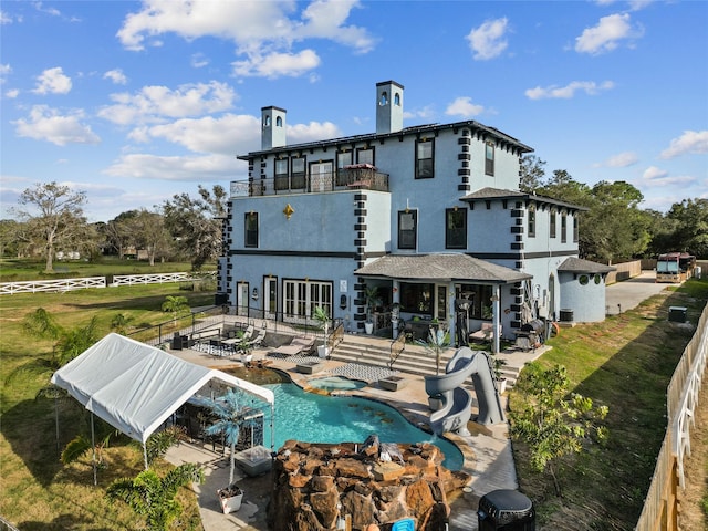 back of property with a patio area, a balcony, and a fenced in pool