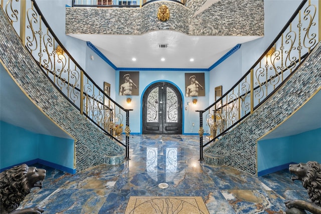 entrance foyer with french doors, ornamental molding, and a high ceiling