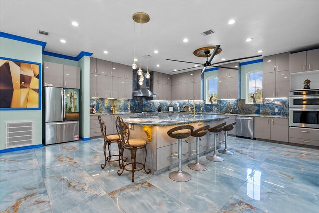 kitchen with gray cabinetry, ceiling fan, a center island, and appliances with stainless steel finishes