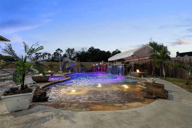 pool at dusk featuring pool water feature