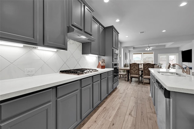 kitchen featuring appliances with stainless steel finishes, gray cabinetry, ceiling fan, sink, and light hardwood / wood-style flooring