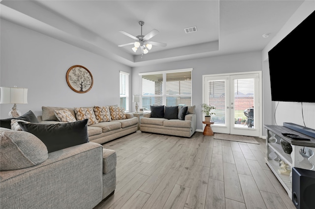 living room with ceiling fan, french doors, a wealth of natural light, and light hardwood / wood-style flooring