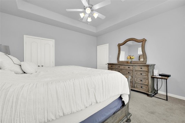 bedroom featuring light colored carpet, ceiling fan, and a tray ceiling