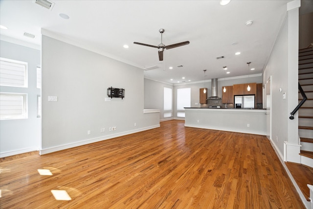 unfurnished living room featuring light hardwood / wood-style floors, ceiling fan, and ornamental molding