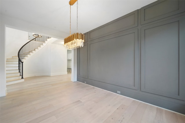 unfurnished dining area with light wood-type flooring and an inviting chandelier