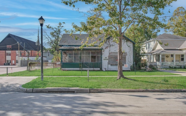 view of front of property with a sunroom and a front lawn