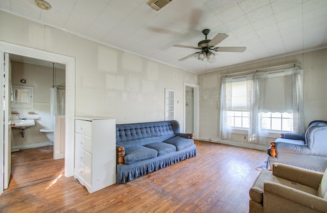 living room featuring crown molding, hardwood / wood-style floors, ceiling fan, and sink