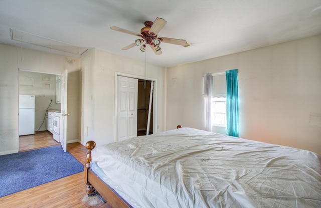 bedroom with ceiling fan, white fridge, wood-type flooring, and a closet