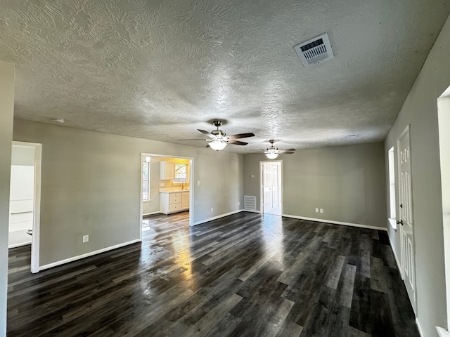 unfurnished living room featuring ceiling fan, dark wood-type flooring, and a textured ceiling