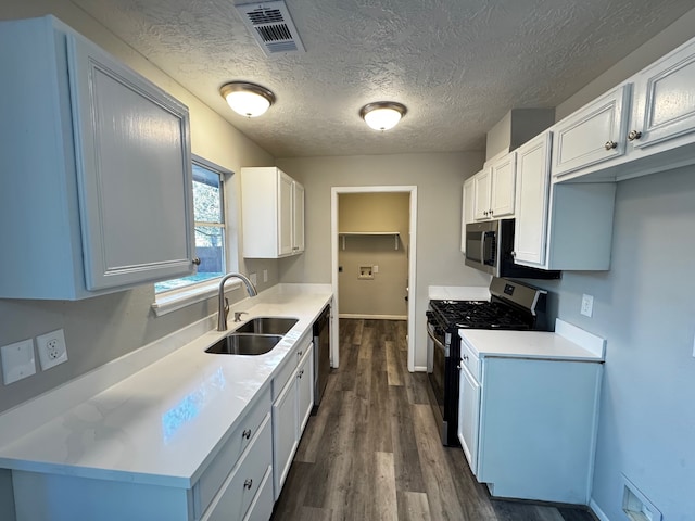 kitchen featuring appliances with stainless steel finishes, a textured ceiling, sink, dark hardwood / wood-style floors, and white cabinetry