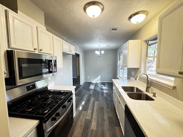 kitchen with dark wood-type flooring, sink, light stone countertops, appliances with stainless steel finishes, and decorative light fixtures