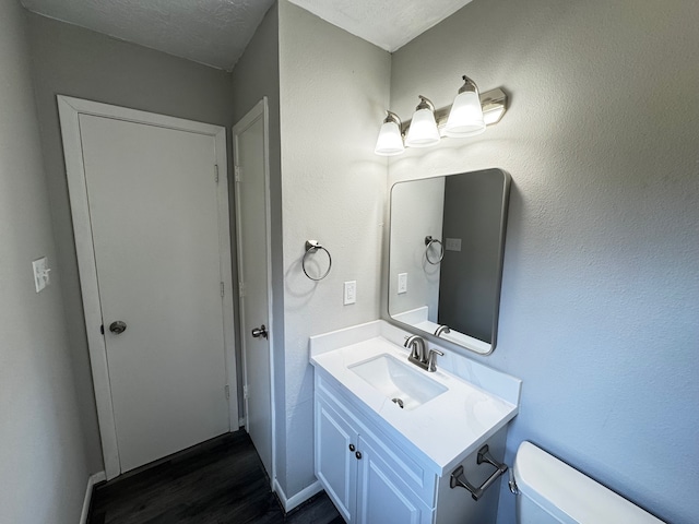 bathroom with toilet, vanity, a textured ceiling, and hardwood / wood-style flooring