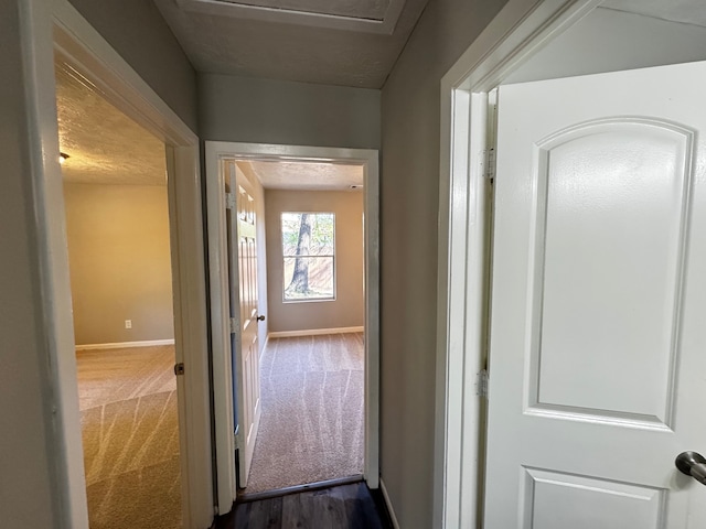 hallway featuring dark colored carpet