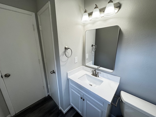 bathroom with hardwood / wood-style floors, vanity, and toilet