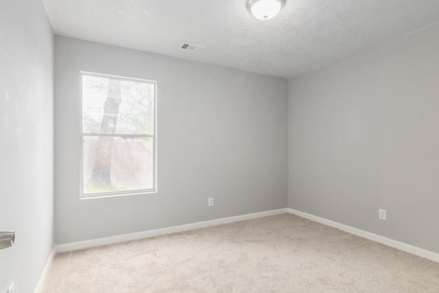 carpeted empty room featuring visible vents, baseboards, a textured ceiling, and a healthy amount of sunlight