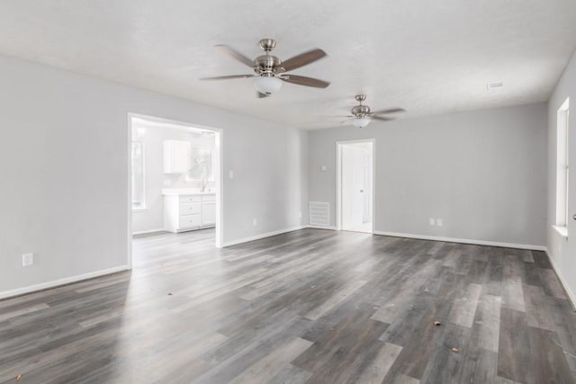 spare room featuring dark wood-style floors, baseboards, and a sink