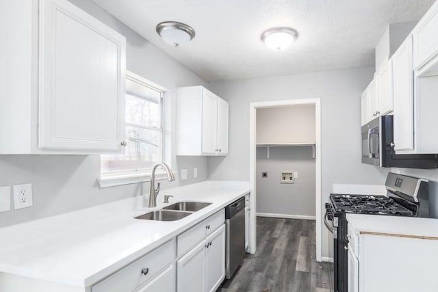 kitchen featuring a sink, dark wood-type flooring, white cabinets, light countertops, and appliances with stainless steel finishes