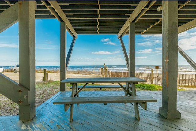 exterior space with a deck with water view and a beach view