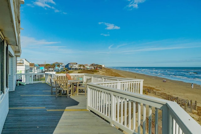 wooden deck featuring a beach view and a water view