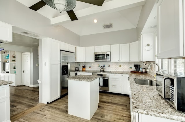 kitchen featuring light stone countertops, appliances with stainless steel finishes, light wood-type flooring, and a kitchen island