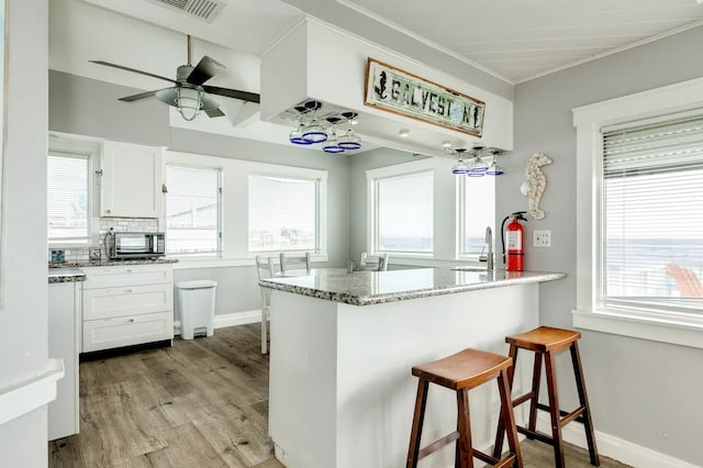 kitchen with a wealth of natural light, white cabinetry, and light hardwood / wood-style floors