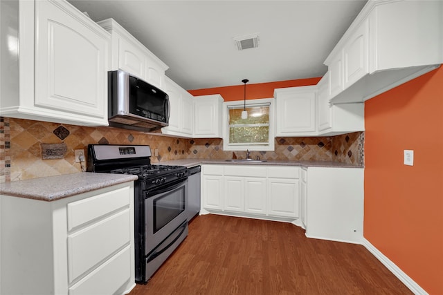 kitchen featuring sink, decorative light fixtures, white cabinets, dark hardwood / wood-style floors, and appliances with stainless steel finishes