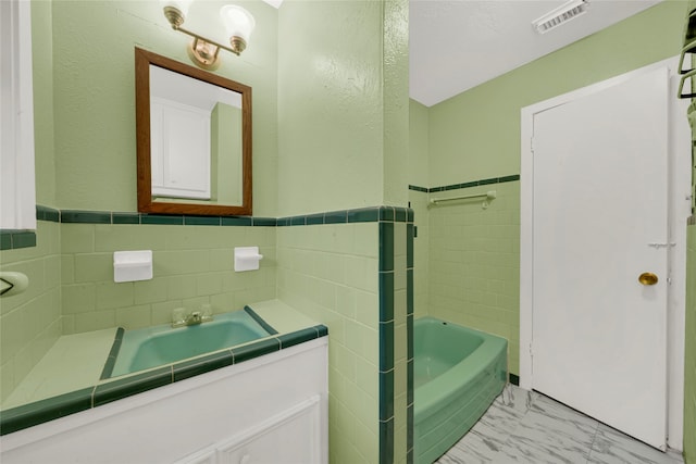 bathroom featuring vanity, tile walls, and a bath