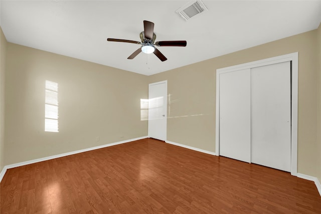 unfurnished bedroom with hardwood / wood-style flooring, ceiling fan, and a closet