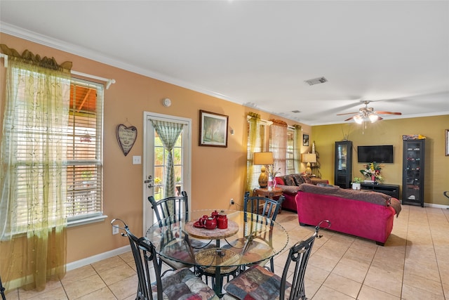 tiled dining area with ceiling fan and ornamental molding