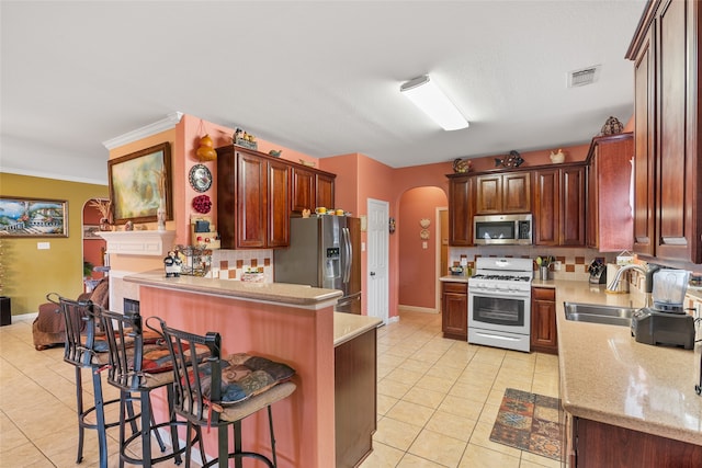 kitchen featuring ornamental molding, a breakfast bar, stainless steel appliances, sink, and light tile patterned floors