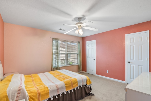 bedroom featuring ceiling fan, light carpet, and a textured ceiling