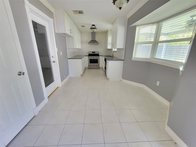 kitchen with wall chimney range hood, sink, stainless steel stove, tasteful backsplash, and white cabinetry