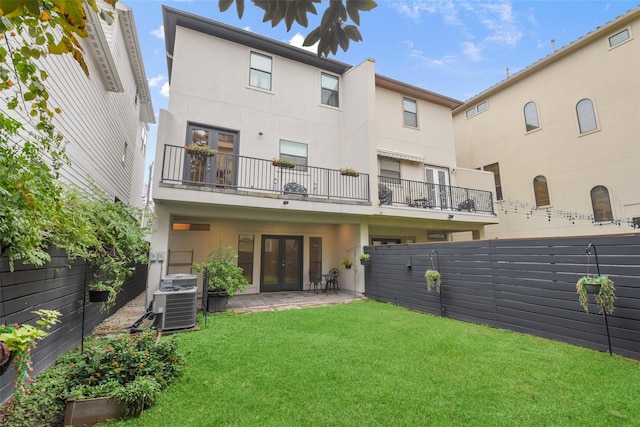 rear view of property featuring a lawn, central air condition unit, a patio, and french doors