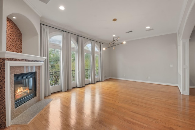 unfurnished living room with a chandelier, ornamental molding, and light hardwood / wood-style flooring